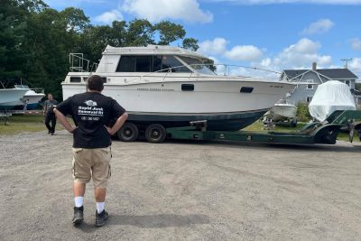 Rapid Junk Removal RI hauling a large boat in Warwick, Rhode Island using a hydraulic boat trailer for professional boat removal and disposal.